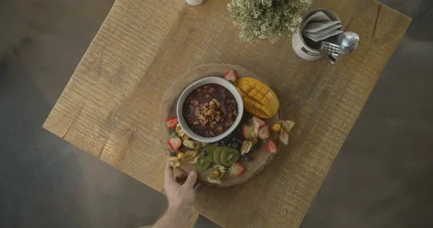 Top view of man's hand spinning plate with smoothie and fruit mix on the table Stock Footage 103800486