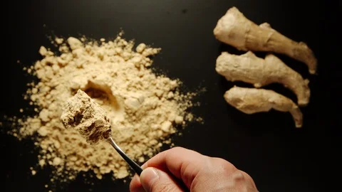 TOP VIEW: Man's hand taking a teaspoon of yellow ginger powder from a pile Stock Footage 108199232