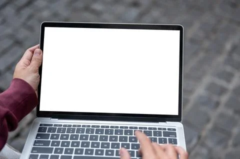 Top view of a man's hand typing on white screen laptop while sitting on ben.. Fotos Stock