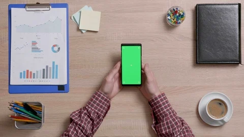 Top view of a man's hands holding his smartphone and looking at a green screen. Stock Footage 105516625