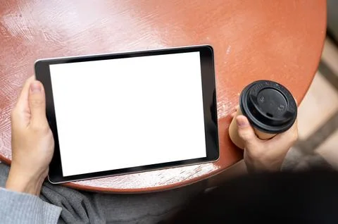 Top view of a man's hands holding coffee looking at white screen tablet whi.. Stock Photos