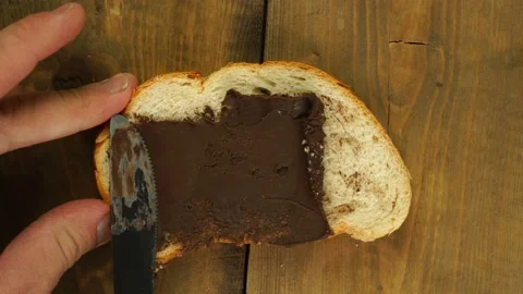 Top view of man's hands spreading chocolate paste on wholemeal toast on wooden Stock Footage 168186201