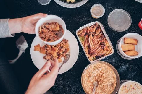 Top view of a man's hands on a table full of Chinese food. Stock Photos