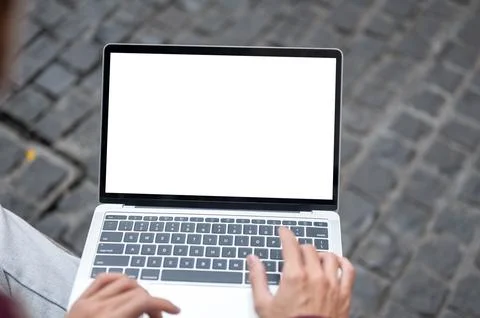 Top view of man's hands typing on white screen laptop while sitting on benc.. Stock Photos