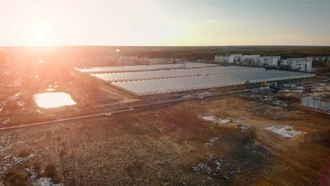 Top view of many large, newly built glass greenhouses rectangular in the sunset Stock Footage 104075418