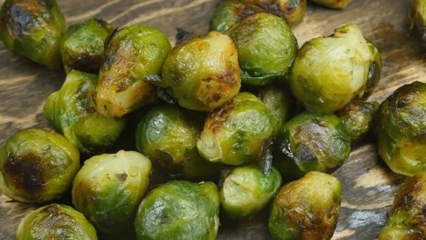 Top view of many sprouts of roasted brussels sprouts on a brown wooden plane Stock Footage 160428396