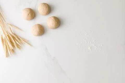 Top view of a marble table with four molded bread dough, wheat and flour with Stock Photos