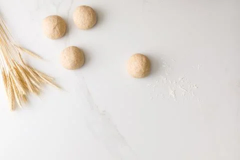 Top view of a marble table with three molded bread dough close and one far, w Stock Photos