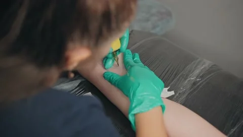 Top view master beats tattoo with help machine on client arm in couch studio. Stock Footage 219549557