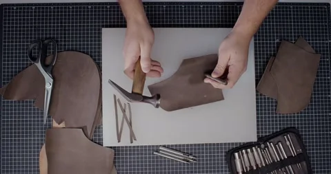 Top view of master makes holes in leather piece to make shoes in 4k resolution Stock Footage 200127230