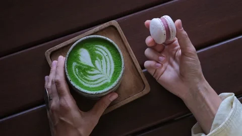 Top view of matcha mug with green foam in the shape of a heart. Women's hands Stock Footage 178381651