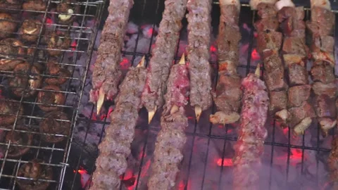 Top View of Meat Skewers Roasting Over Charcoal With Rising Smoke Stock Footage 336976342