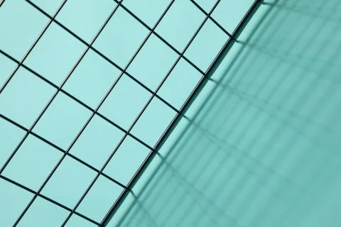 Top view of a metal grid casting shadows on a cyan background 写真素材