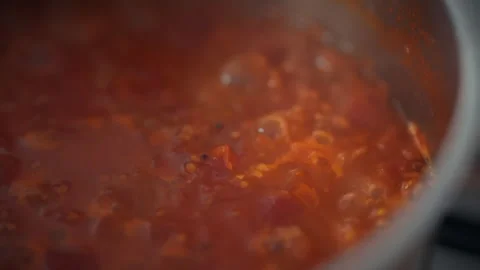 Top view of a metal pot with boiling tomato sauce on the stove. Tomato pulp 動画素材 345579972
