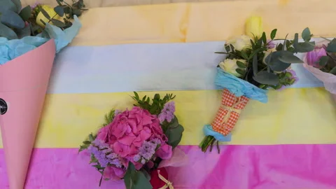 Top view of mini bouquets of fresh flowers in colorful packaging on a bright sum 스톡 동영상 307088914