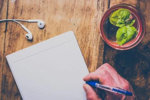 Top view of minimal workspace with blank notepad, pen, earphones and glass of Stock Photos