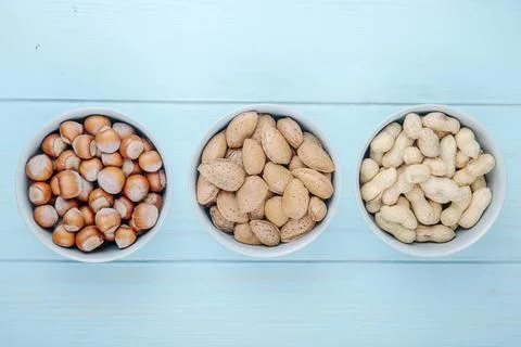 Top view of mixed nuts hazelnuts almond and peanuts in shell in bowls on bl.. Stock Photos