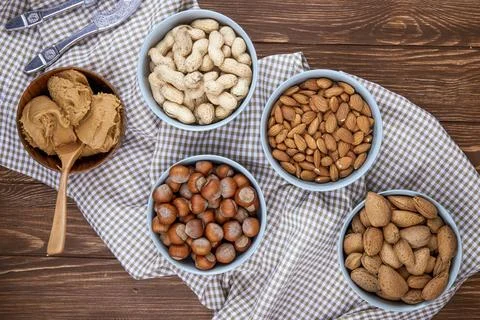 Top view of mixed nutsin shells in bowls peanuts hazelnuts almonds on plaid.. Stock Photos