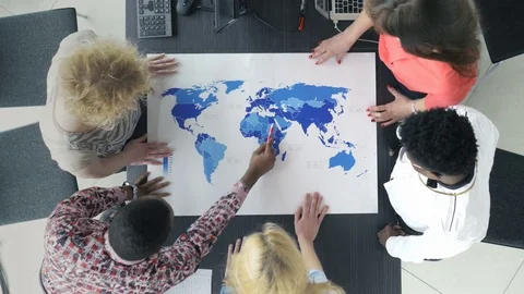 Top view of mixed-race group examining the world map Stock Footage 73849468