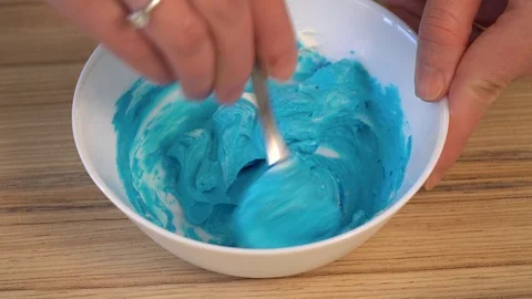 Top view of mixing the cream for decorating and dye in the bowl. Cooking Stock Footage 86768216
