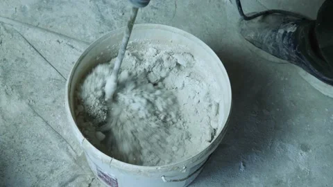 Top view of mixing plaster in a bucket with a hand-held electric mixer Stock Footage 164717290