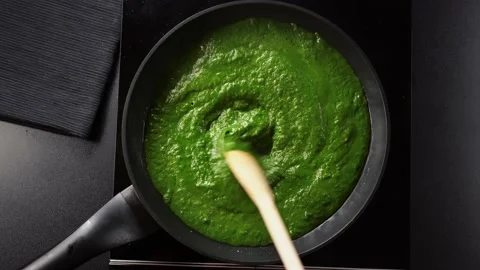 Top view of mixing spinach puree in frying pan on stove Stock Footage 146912565