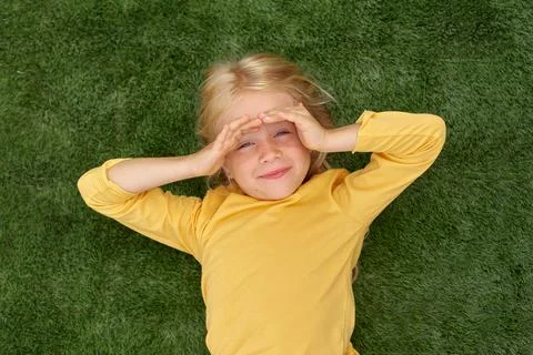 Top view. Mock up for logo, text, design. Blonde long hair child girl lying o 库存照片