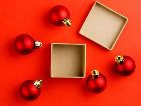 Top view mock up open present box with red christmas balls on red background Stock Photos