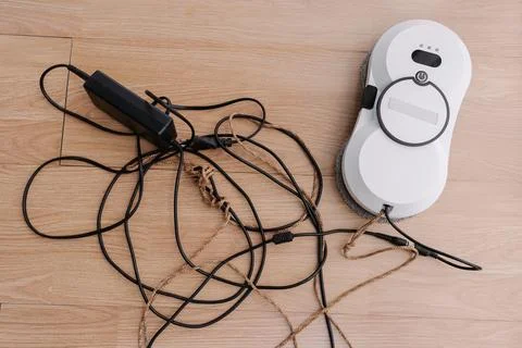 Top view of modern white window cleaning robot lying on floor, resting beside Stock Photos