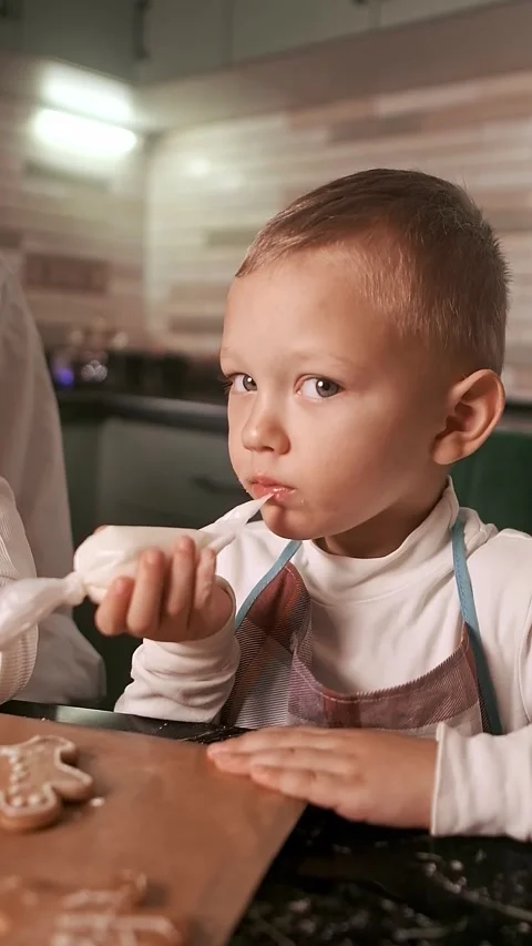 Top view of a mother and children decorating gingerbread cookies with icing, enj Stock Footage 288451237