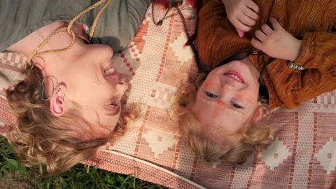 Top view of mother talking to her daughter laying on the picnic plaid. Boho Stock Footage 146925680