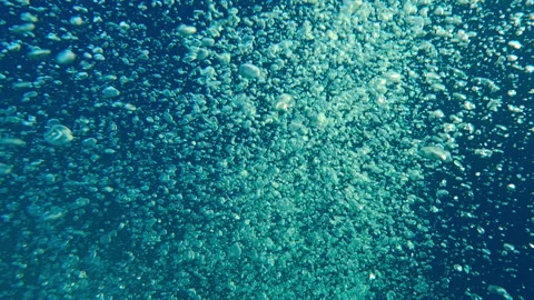 Top view of motion of air bubbles popping up to surface against deep blue sea Stock Footage 331476050