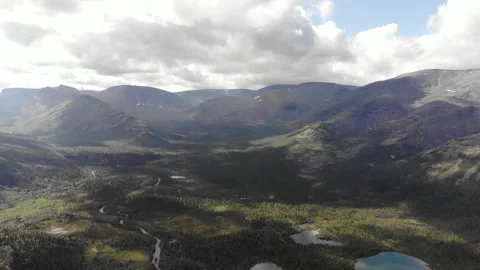 Top view of a mountain valley with forests around a small lakes and a dirt road Stock Footage 164373206
