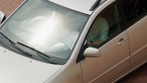 Top view of moving white car with reflective windshield sunshade protecting Stock Footage 336901830