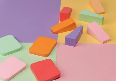 Top view of multi-colored sponges on different pastel-colored backgrounds. Ab Fotos de archivo