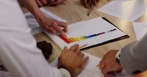 Top view of multi-ethnical hands with pencils analyzing and dealing with paper Stock Footage 82445898