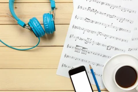 Top view music sheet note paper,headphones,smartphone,pencil,coffee on wood Stock-Fotos