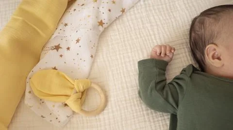 Top view of newborn tiny hand on a pastel blanket. Baby kid on the bed. Stock Photos