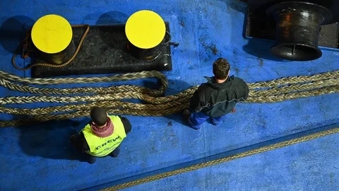 Top view at night of crew handling a rope for mooring maneuvers of a ship Stock Footage 105167597