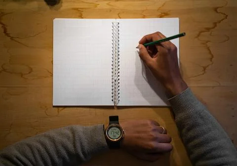 Top view of note book with hand on wood background office desk  , hand writing o 库存照片