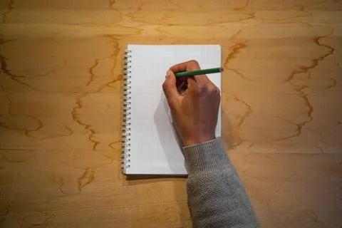 Top view of note book with hand on wood background office desk  , hand writing o 库存照片