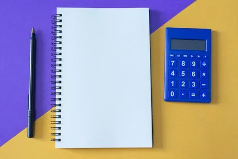 Top view of note pad, pen, and calculator on multi colored background Stock Photos