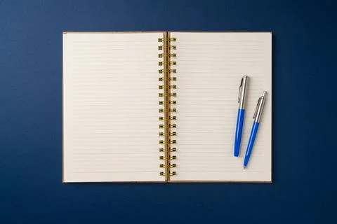 Top view of notebook and ballpoint pen on blue background Stock Photos