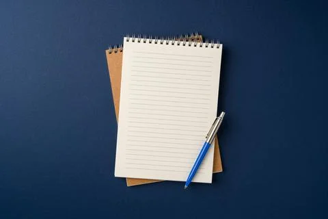 Top view of notebook and ballpoint pen on blue background Stock Photos