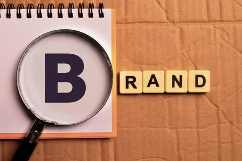 Top view of notebook and magnifying glass with text BRAND. Business concept. Stock Photos