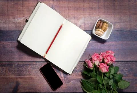 Top view of notebook and pink roses flowers on rustic brown wooden table. Foto stock