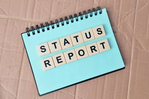 Top view of notebook and square letters with text STATUS REPORT. Stock Photos