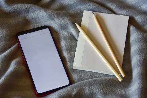 Top view of a notebook and two pencils, a smartphone with breaking news on th Stock Photos