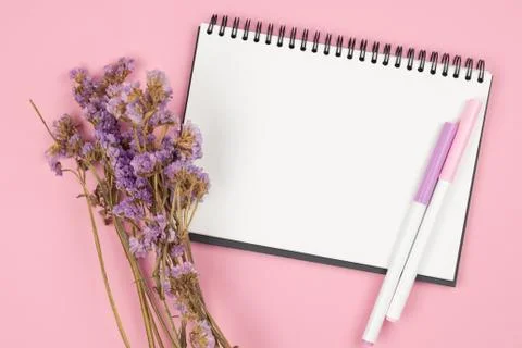 Top view of notebook and violet flower on pink background Foto stock
