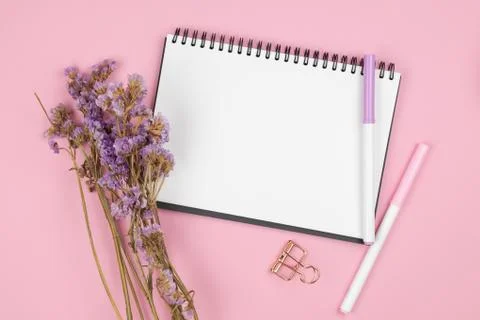 Top view of notebook and violet flower on pink background Foto stock